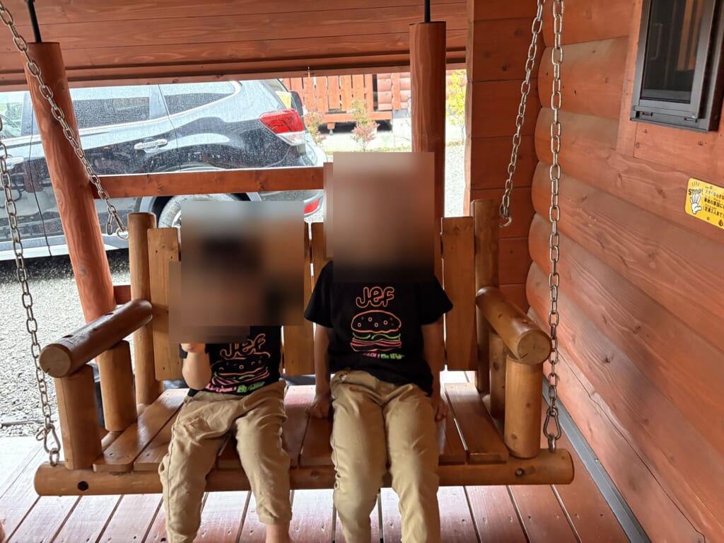 TAKIBIの屋根付きデッキのブランコに座る子ども2人